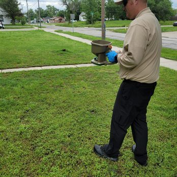 Brandon spreading a granular treatment across a front lawn