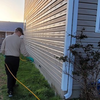 Brandon spraying along the base of a house